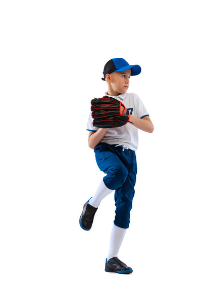 Sportive kid, beginner baseball player in sports uniform with glove and ball isolated on white background. Concept of sport, achievements, competition. School age boy learning to play baseball - 写真・画像