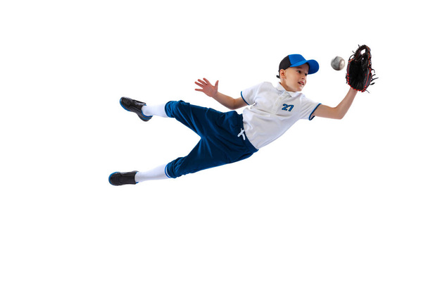 Little beginner baseball player in sports uniform playing baseball isolated on white background. Concept of sport, achievements, competition. School age boy learning to play baseball - Fotografie, Obrázek