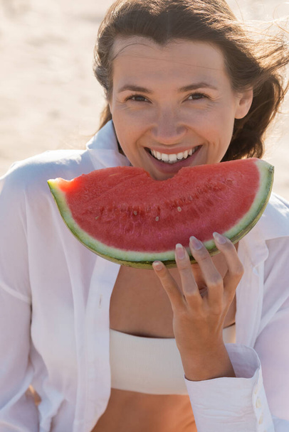 portrait of happy young woman in white shirt holding tasty watermelon - Foto, Bild