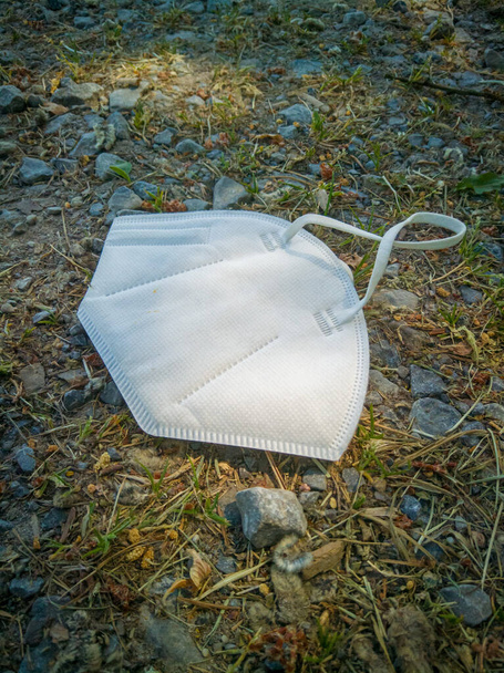 discarded FFP2-mask lies on agricultural road. A symbol of garbage and pollution. - Photo, Image