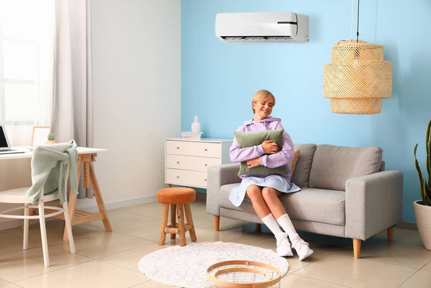 Nuori nainen rentouttava mukava sohva huoneessa kytketty ilmastointilaite - Valokuva, kuva