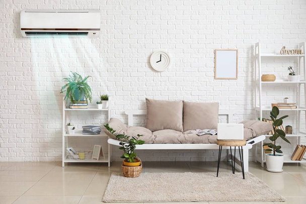 Stilvolles Interieur eines hellen Wohnzimmers mit Sofa, Regaleinheiten und Klimaanlage - Foto, Bild