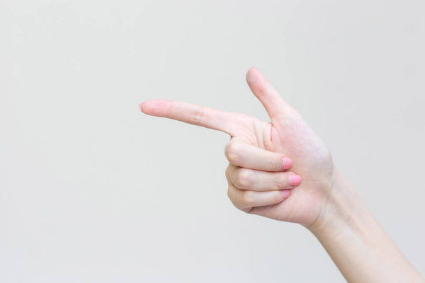 Hermosa mano femenina muestra el dedo como un símbolo que apunta en el concepto de manicura para presentar algo en el fondo blanco. - Foto, Imagen