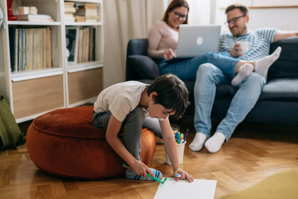 family spending time together at home. boy drawing , mother and father using laptop - Fotoğraf, Görsel
