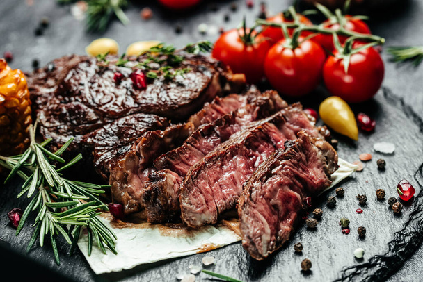 Sliced steak ribeye, grilled on a dark stone background. Restaurant menu, dieting, cookbook recipe top view. - 写真・画像