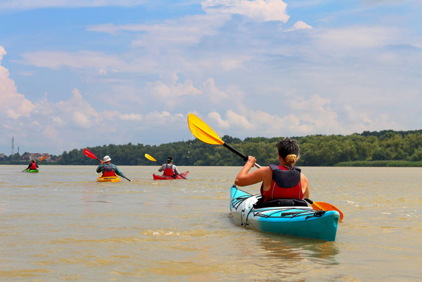 Gruppo di amici (persone) viaggiare in kayak. Kayak insieme nel fiume Danubio selvaggio e riserva della biosfera in estate. Scena naturale tranquilla di fiume calmo. Il concetto di turismo acquatico - Foto, immagini