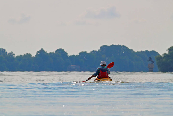 Widok z tyłu kajakarz człowiek wiosła żółty kajak na Dunaju rzeki. Letni kajak. Koncepcja przygody, podróży, akcji, stylu życia - Zdjęcie, obraz