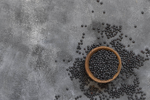 Wooden bowl of black beluga lentils beans on grey table top view.  Healthy eating, protein source for vegan and vegetarian diet. Traditional Asian and North African cuisines ingredient - 写真・画像
