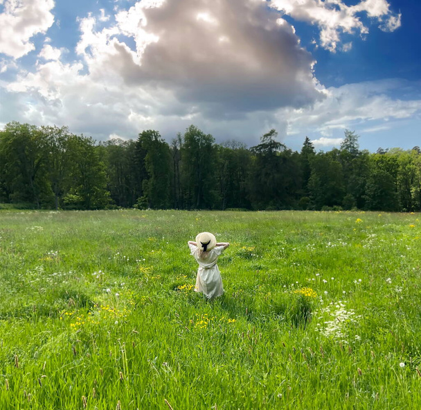  Frau auf wildem Feld mit blühenden gelben Blumen und hellem Himmel mit weißen Wolken Sommer Naturlandschaft, grünes Gras Kräuter Landschaft Lifestyle-Szene  - Foto, Bild