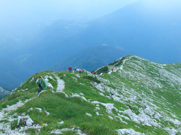 Groepen van mannen met toeristische uitrusting in rugzak in trekking naar de top van de berg. Toeristen met rugzakken op hun rug lopen langs de bergketen. Verovering van nieuwe pieken. Actieve manier van leven. Reizigers die wandelen op een bergachtig pad. Opstijgen - Foto, afbeelding
