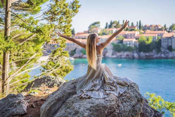 Γυναίκα τουρίστρια στο φόντο της όμορφη θέα του νησιού του Αγίου Στεφάνου, Sveti Stefan στην Budva Riviera, Budva, Μαυροβούνιο. Ταξίδι στο Μαυροβούνιο. - Φωτογραφία, εικόνα