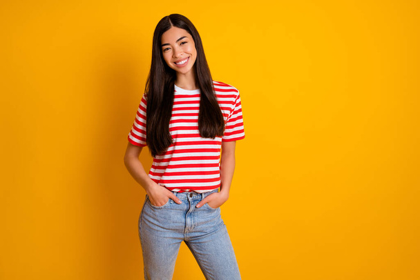 Photo of sweet cute young woman dressed striped outfit hands pockets empty space isolated yellow color background. - Valokuva, kuva