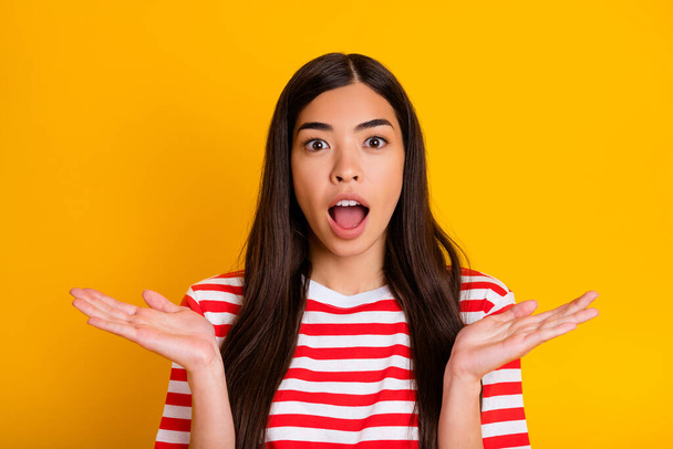 Photo of adorable funky young woman dressed striped outfit rising arms open mouth isolated yellow color background. - Φωτογραφία, εικόνα