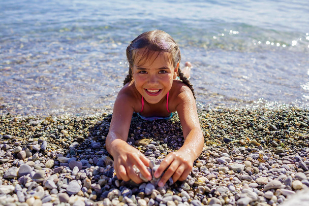 Mutlu kız portresi Cenevre Gölü 'ndeki çakıl taşlı sahilde güneş ışığında mavi dağların üzerinde eğleniyor. Bol bol eğlence ve mutluluk, yaz tatili, seyahat ve yaz tatili, yaşam tarzı. - Fotoğraf, Görsel