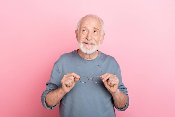 Photo of funky dreamy guy pensioner dressed grey pullover arms glasses looking empty space isolated pink color background. - Foto, immagini
