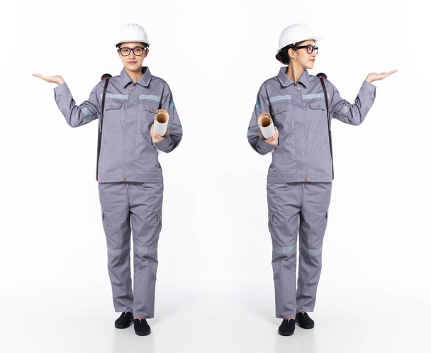 Full length 30s 40s Asian Woman Engineer Τεχνικός βιομηχανίας, με άδειο χέρι παλάμης, φοράει επίσημο ομοιόμορφο εξοπλισμό ασφαλείας. Χαμόγελο εργοστάσιο θηλυκό μεταφέρουν σωλήνα σχέδιο πάνω από λευκό φόντο απομονωμένο - Φωτογραφία, εικόνα