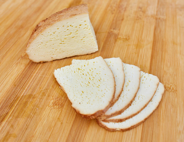 hausgemachter geräucherter Käse in Scheiben geschnitten auf einem Holzbrett - Foto, Bild