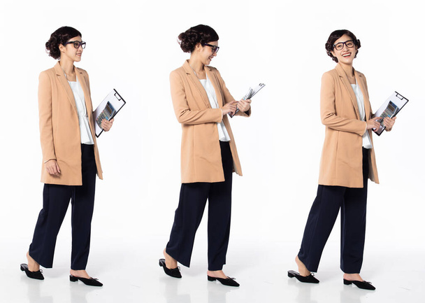 Full length 30s 40s Asian Woman Tax Financial Accountant, walking forward left right, wear formal blazer pants shoes. Smile Office female carry calculator folder over white background isolated - Fotó, kép
