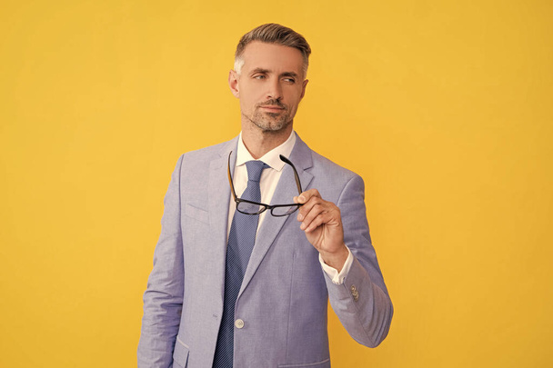 mature man in businesslike suit hold glasses on yellow background, vision. - Photo, Image