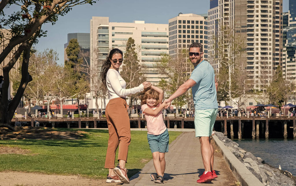 Вид сзади на молодую семью, гуляющую в парке с ребенком, дружба. - Фото, изображение