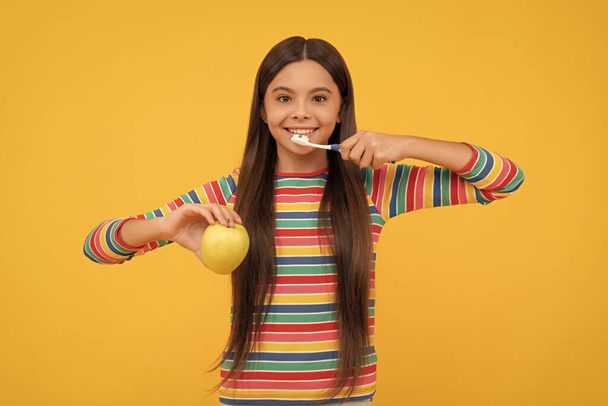 Mosson fogat naponta kétszer. Boldog gyermek fogmosás kezében alma. Szájhigiénia. Fogászati egészség. Fog- és fogínyápolás. - Fotó, kép