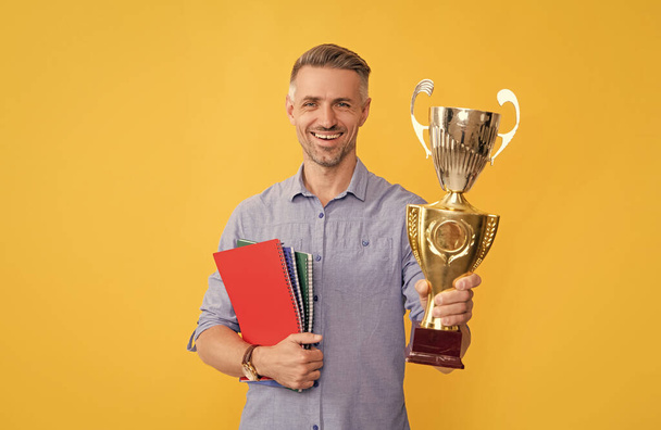guy celebrate victory. inspiration and motivation. happy mature man hold golden cup and notebooks. achievement award. motivation of business success. trophy and prestige. got prize. - Photo, Image