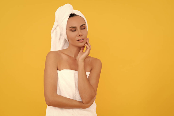 young woman in towel after shower on yellow background with copy space. - Foto, imagen
