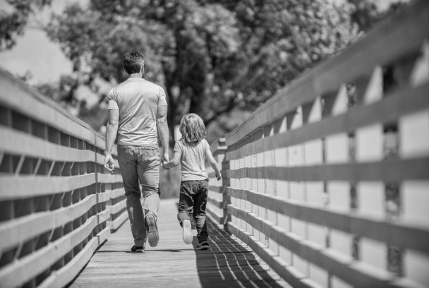szczęśliwy ojciec prowadzi z jego dziecko spacery na zewnątrz, widok z tyłu, rodzicielstwo. - Zdjęcie, obraz