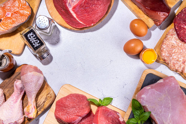 Carnivore diet background. Various non-vegan protein sources, Traditional Carnivore food - meat and fish, chicken breast, pork steak, beef steak, patty, heart, liver, eggs with spices for cooking - Foto, afbeelding