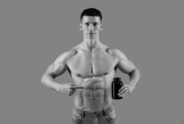 Supplements worth taking. Shirtless man point finger at protein bottle. Dietary supplements. Sports nutrition. Advertising gesture, copy space. - 写真・画像