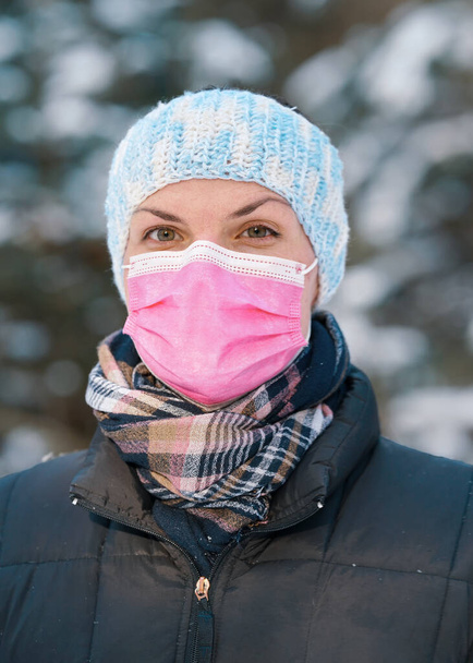 Young woman in winter jacket with pink disposable single use face virus mask - Foto, immagini