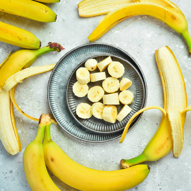 Fresh bananas sliced in a bowl. Tropical bananas on a gray concrete background. Top view. - Фото, зображення