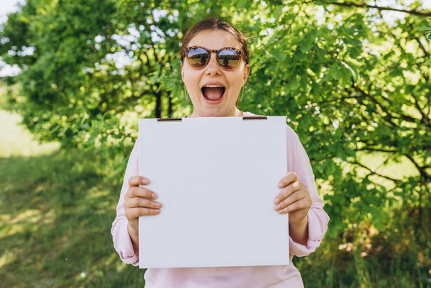 Γυναίκα χέρια κρατώντας ένα κουτί με πίτσα στο φόντο της φύσης. Γρήγορη παράδοση πίτσας. Mock επάνω. Fast food banner, καλοκαίρι - Φωτογραφία, εικόνα