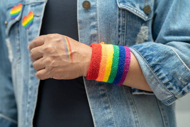 Asian lady wearing rainbow flag wristbands, symbol of LGBT pride month celebrate annual in June social of gay, lesbian, bisexual, transgender, human rights. - Photo, Image