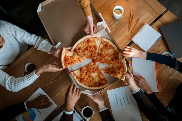 koledzy z najwyższej półki jedzący pizzę podczas przerwy biurowej. Zdjęcie w wysokiej rozdzielczości - Zdjęcie, obraz
