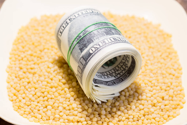 Banconote in contanti su grani di couscous. L'aumento dei prezzi dei prodotti alimentari in Ucraina a causa della guerra - Foto, immagini
