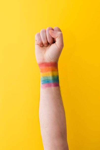 person holding fist with rainbow flag wrist. High resolution photo - Foto, imagen