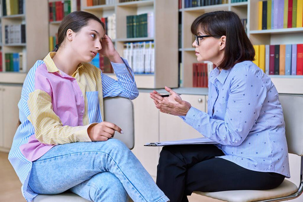 Psychologist, teacher, behavior, high school counselor counseling teenage student in library, office. Psychological help, social work, mental health, adolescence, youth psychotherapy psychology - Photo, image