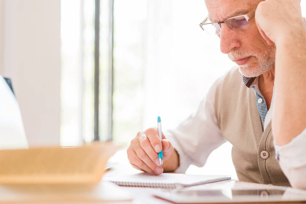 Profesor sénior de gafas escribiendo clases de cuaderno. Foto de alta resolución - Foto, Imagen