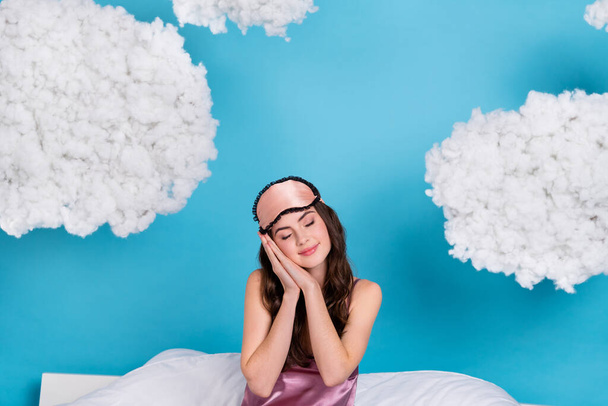 Portrait of attractive dreamy calm sweet girl sitting on cosy bed sleeping sleepover isolated over bright blue color background. - Foto, immagini