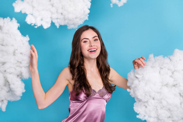 Portrait of attractive cheerful wavy-haired girl touching cotton clouds flying isolated over bright blue color background. - Foto, Imagen