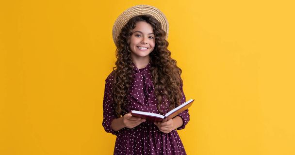 happy kid with frizz hair read book on yellow background. - Фото, изображение