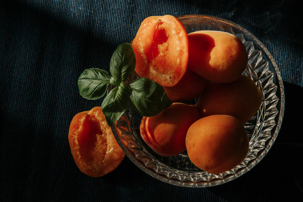 Fresh juicy orange apricots in a plate, half an apricot, apricots on the table, summer fruits and berries, vitamins and healthy nutrition - Photo, image