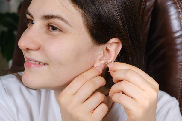 Egy nő arany fülbevalót vesz fel a fülébe. - Fotó, kép