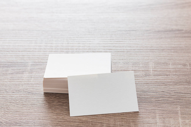 On a table is a stack of blank textured cardboard business cards. One of them is leaning on the stack facing the frame. - Fotoğraf, Görsel