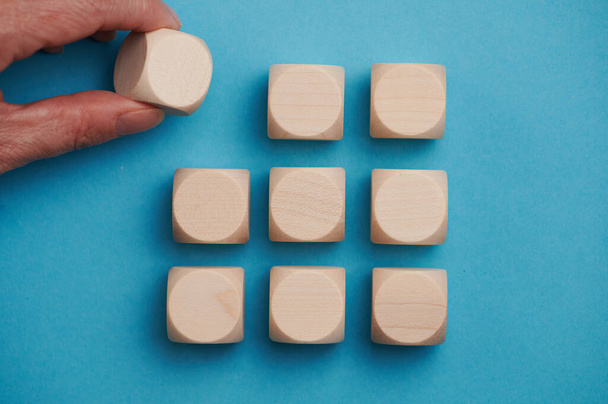 Neuf cubes en bois sur un fond bleu debout l'un sur l'autre en trois rangées. La main fwmale ajoute le cube supérieur gauche, espace libre pour les lettres, les chiffres, les symboles - Photo, image