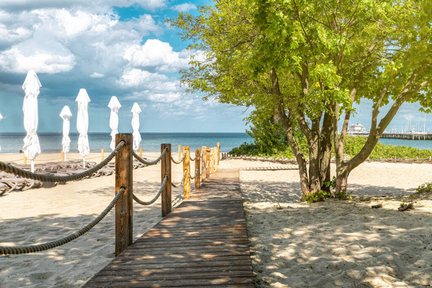 Passerelle en bois sur une plage de sable ensoleillée - Photo, image