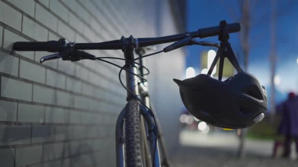 Sisak piros jelzőlámpával a bicikli kormányán a városban éjszaka. A téma a kerékpárosok biztonsága a sötétben. Kerékpár hátsó lámpa egy kerékpár sisak. Elemlámpa és hátsó piros lámpa - Felvétel, videó