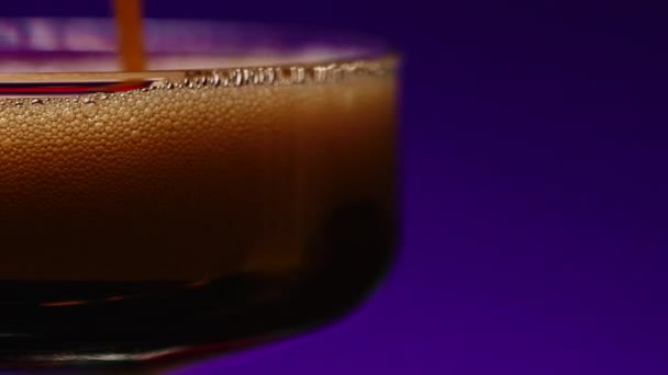 Primer plano de verter alcohol carbonatado afrutado en vidrio. Clip de stock. Cóctel en el bar nocturno sobre un colorido fondo de pared - Metraje, vídeo