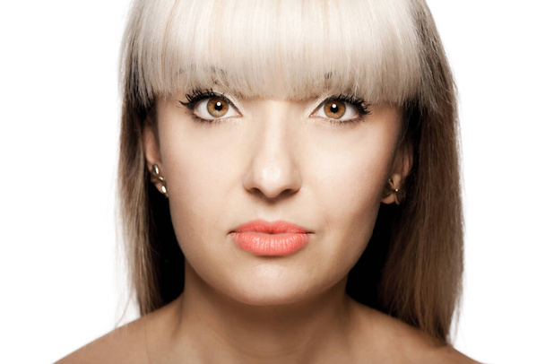 Close up portrait of a beautiful brunette girl with blond bangs fringe. Serious face expression - Фото, изображение